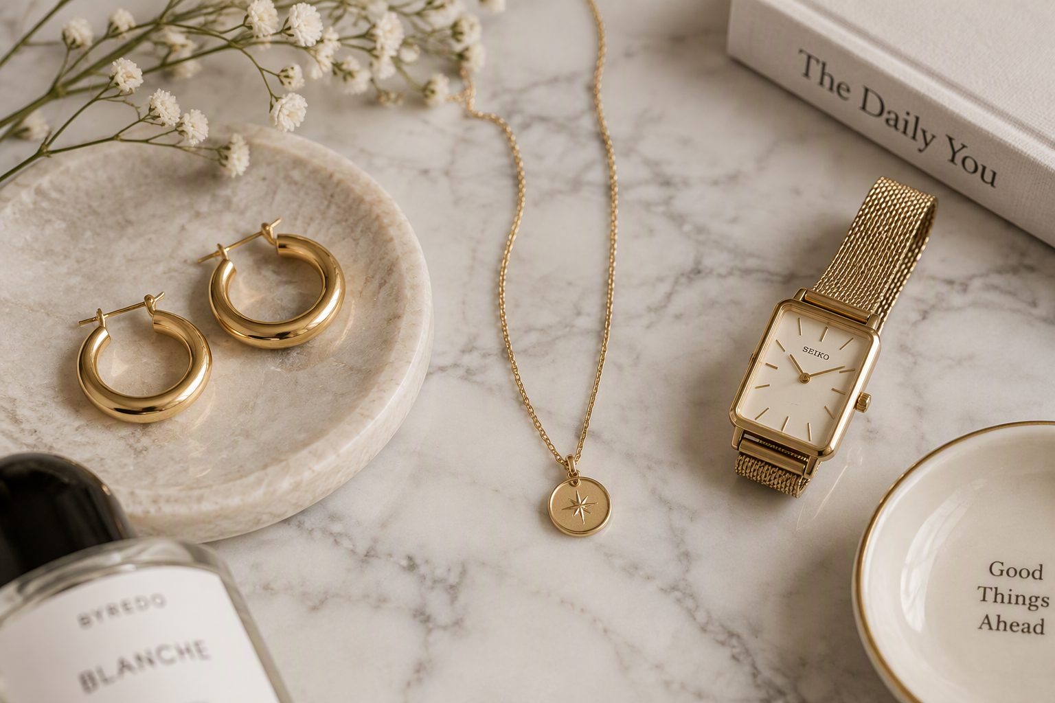 A curated collection of minimalist jewelry and accessories on a marble surface